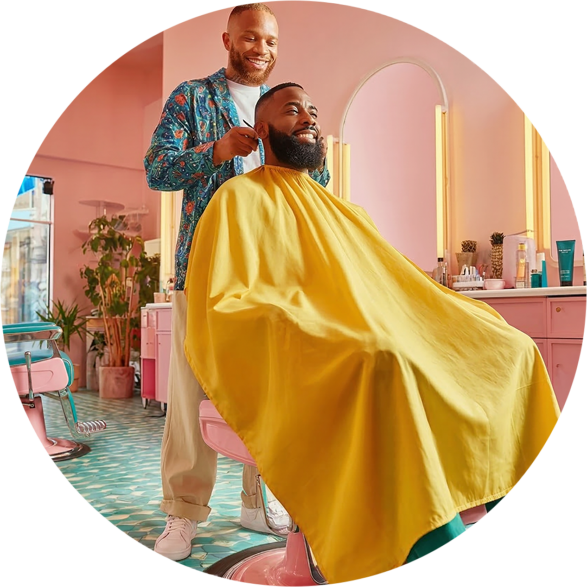 Man met baard zit in de kappersstoel en wordt geknipt door een kapper